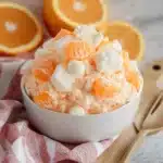 orange fluff in a white bowl next to some oranges