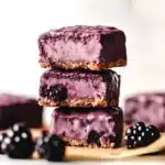 chocolate and raspberry coconut bars stacked on top of each other with text overlay