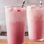 pink coconut iced latte with whipped cream and sprinkles on the side