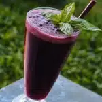 two glasses filled with blueberry soda on top of a table