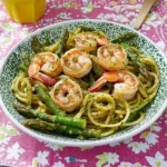 a pasta dish with shrimp, broccoli and tomatoes being stirred with a fork