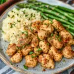 chicken and asparagus in a skillet with lemon wedges