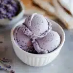 lavender ice cream in a white bowl with green leaves on top and the words lavender ice cream