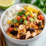 southwest chicken bowl with rice and vegetables on the side, in a white bowl topped with dressing