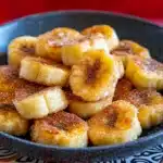 there are bananas that are on the plate with powdered sugar over them and then fried