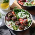 a plate with meatballs, rice and cucumber salad on it next to a fork