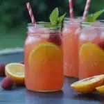 the raspberry peach lemonade cocktail is served in glasses with mint garnish
