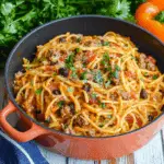two bowls filled with taco spaghetti and topped with cheese