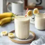 two glasses of milk and bananas on a cutting board with the words korean banana milk