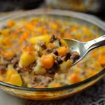 a casserole dish with meat, potatoes and carrots