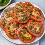 a white plate topped with sliced tomatoes and herbs