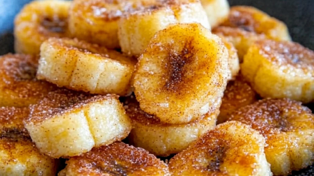 there are bananas that are on the plate with powdered sugar over them and then fried