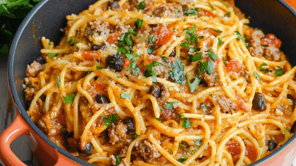 two bowls filled with taco spaghetti and topped with cheese