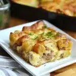tater tot sausage breakfast casserole in a white dish on a wooden table